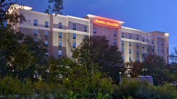 A multi-story hotel with a prominent red sign reading "Hampton Inn & Suites."