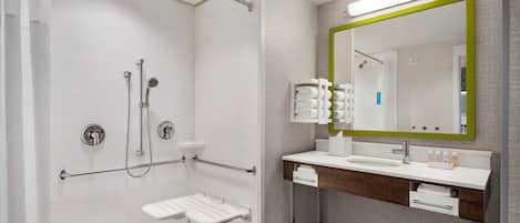 Un baño moderno con cabina de ducha, tocador con espejo y un inodoro.