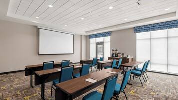 Uma sala de conferências com quadro branco, cadeiras azuis e piso coberto de carpete.