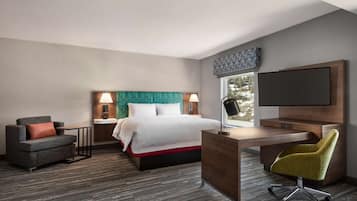 Een moderne hotelkamer met een bed, een bureau, een stoel en een televisie.