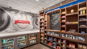 A snack and treat display area with refrigerated sections and shelves stocked with various snacks and packaged goods. - Hampton Inn & Suites by Hilton Kelowna Airport (Kelowna)
