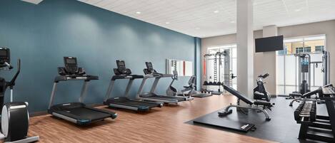 A modern gym with treadmills, elliptical machines, and weightlifting equipment.