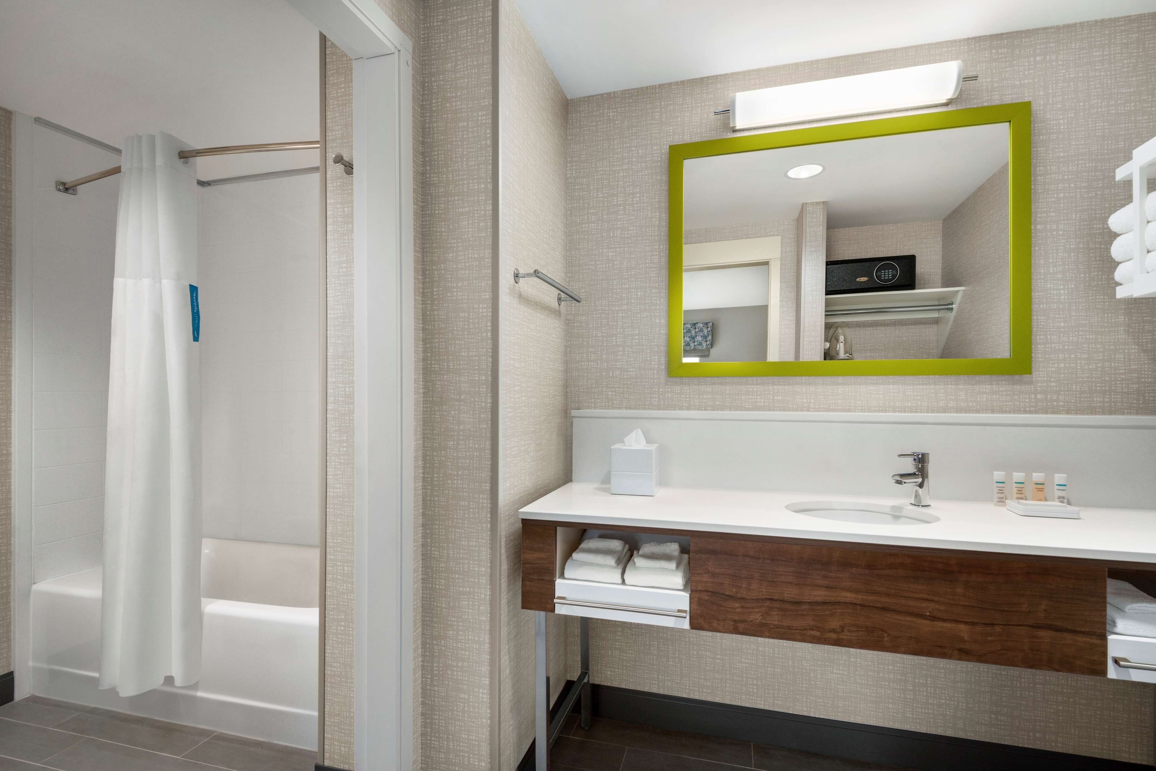 Un bagno moderno con doccia, mobile lavabo con specchio e lavandino.