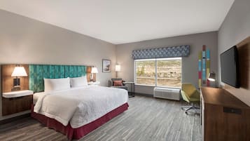 Une chambre d’hôtel avec un grand lit, un bureau, une chaise, une télévision et une fenêtre donnant sur l’extérieur.