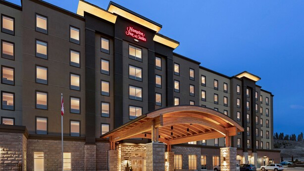 A modern hotel with a prominent entrance, multiple floors, and a stone facade. - Hampton Inn & Suites by Hilton Kelowna Airport (Kelowna)