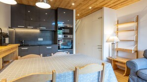 Une cuisine moderne avec des meubles de couleur sombre, des appareils électroménagers en acier inoxydable et un plafond en bois.