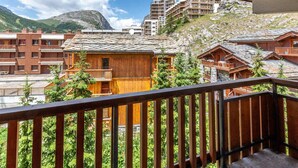 Un bâtiment en bois doté de balcons, entouré de verdure et de montagnes.