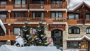 A multi-story wooden building with balconies, a stone facade, and a sign for "Pierre & Vacances Les Chaëtes de Sol."