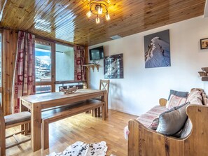 Een gezellige kamer met een houten eettafel, een bank en uitzicht op een besneeuwde berg.