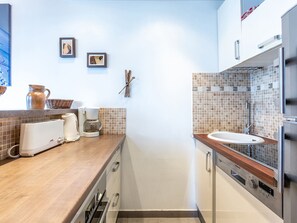 A modern kitchen with a wooden countertop, a coffee maker, a toaster, and a sink.