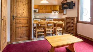 Une cuisine dotée de meubles en bois, d’un four à micro-ondes, d’une cuisinière et d’un coin repas avec une table et des chaises.
