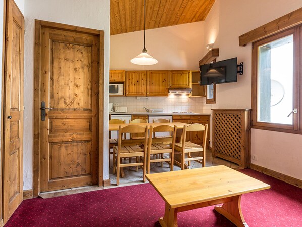 A kitchen with wooden cabinets, a microwave, a stove, and a dining area with a table and chairs.