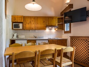 A kitchen with wooden cabinets, a microwave, a stove, and a dining table with chairs.