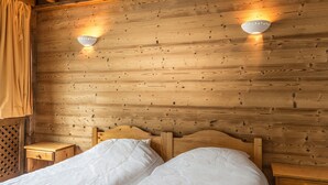 Une chambre de style cabane en bois, avec un lit, deux tables de chevet et des lampes fixées au mur.