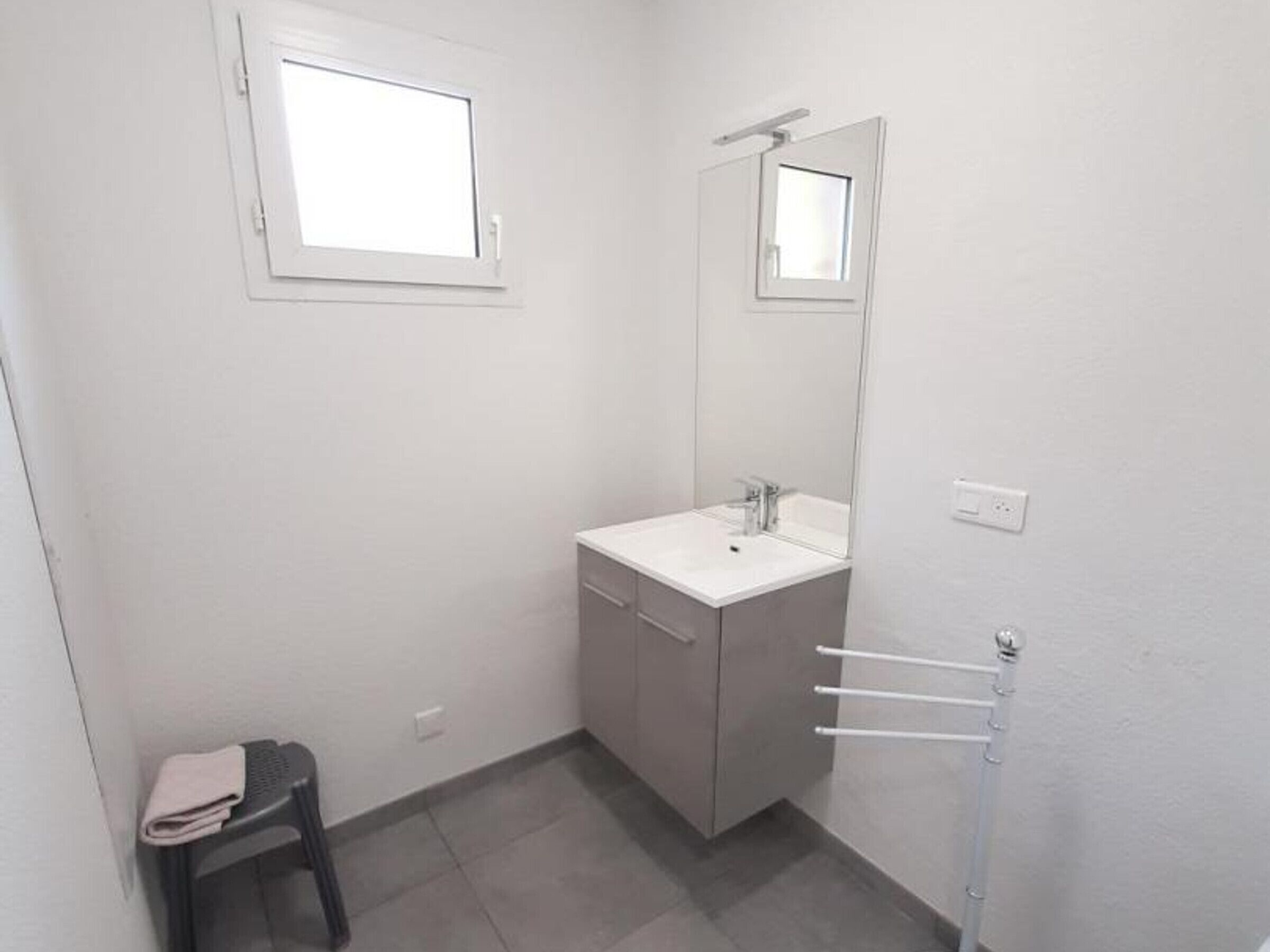 A small, clean bathroom with a white sink, a mirror, and a towel rack.