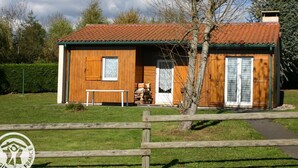 A wooden cabin with a tiled roof, a bench outside, and a wooden fence in the foreground.