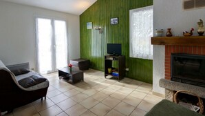 A living room with a sofa, a television on a stand, a fireplace, and a green wall.