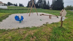 A playground with a seesaw, a swing set, and a blue climbing structure.