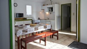 A compact kitchen with a dining table, bench, and basic appliances.