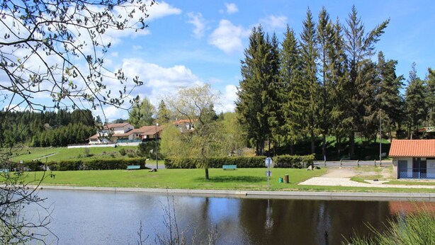 A tranquil park with a pond, benches, and a small building. - Chalet in Usson-en-Forez with fireplace, pets allowed and terrace (Usson-en-Forez)