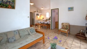 A cozy living room with a sofa, a dining area with a table and chairs, and a kitchen in the background. - Chalet in Usson-en-Forez with fireplace, pets allowed and terrace (Usson-en-Forez)