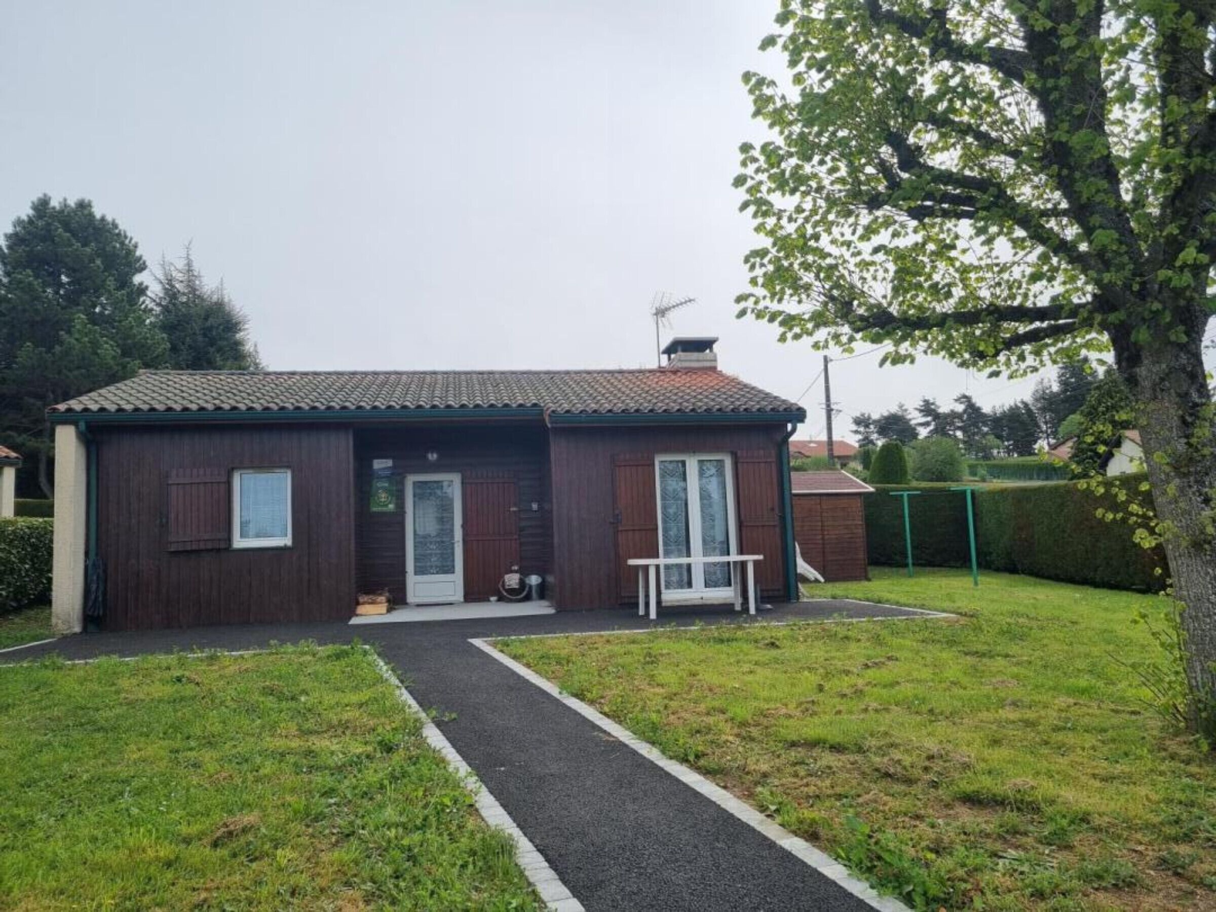 Une petite maison de plain-pied, avec un toit recouvert de tuiles, une porte d’entrée et un petit porche.