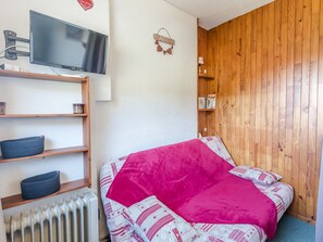 Un dormitorio con cama, estanterías, radiador, televisor y paneles de madera.