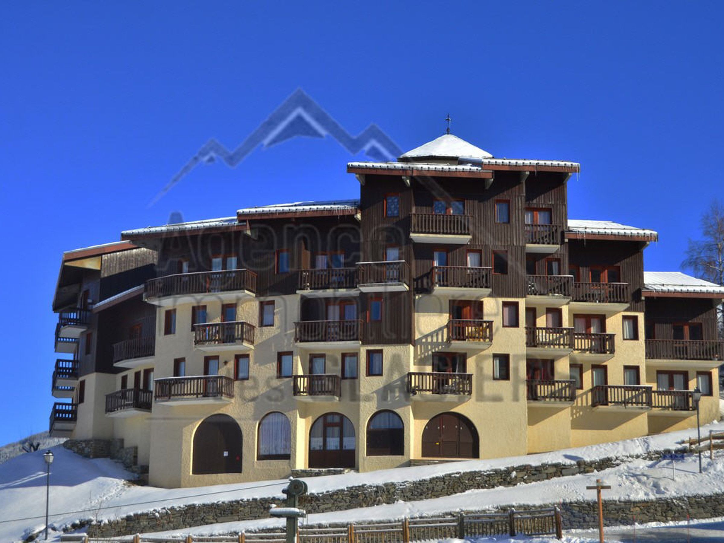 A multi-story hotel with balconies, arched doorways, and a snow-covered landscape.