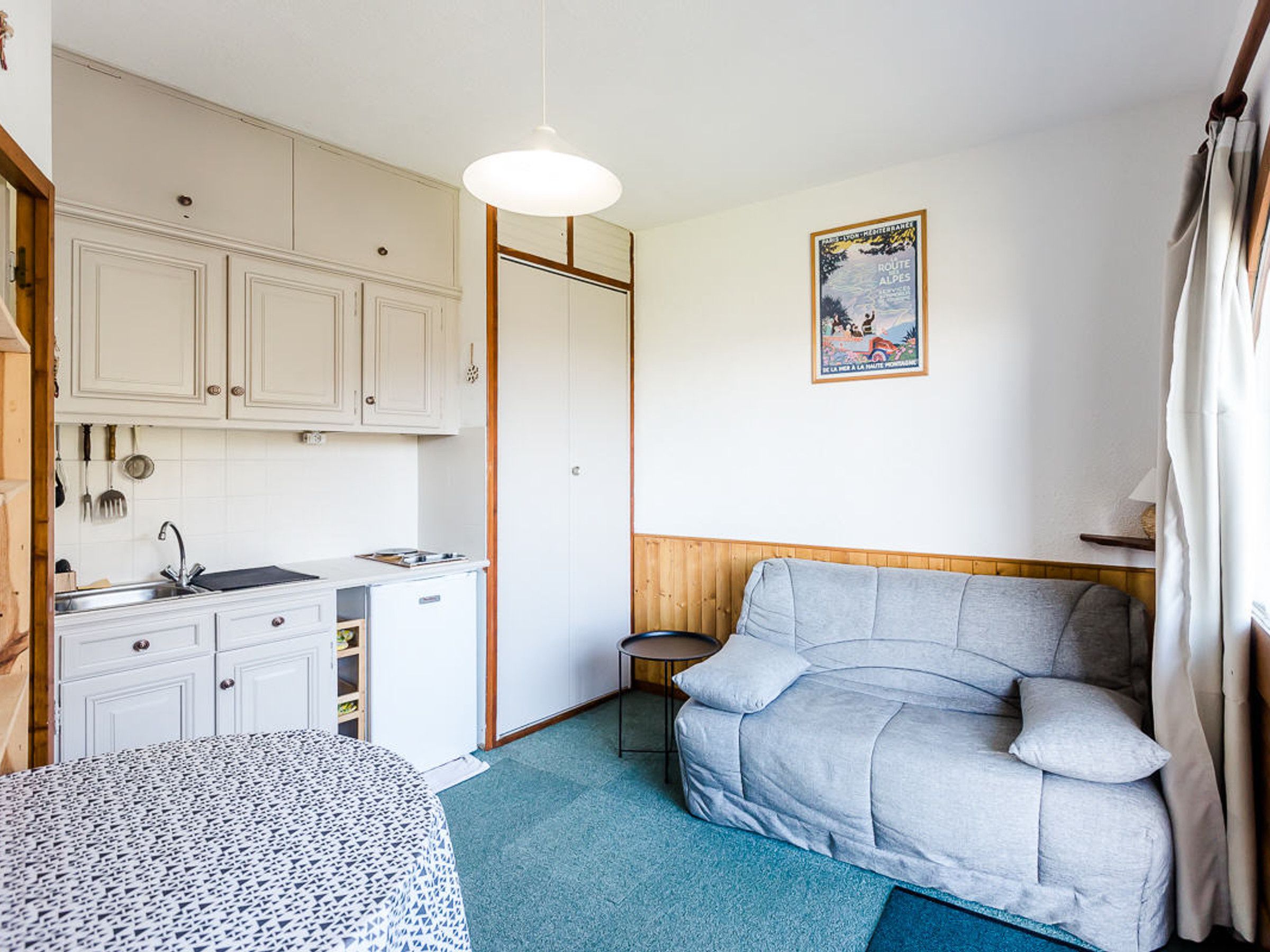 A compact room with a kitchenette, a sofa, and a small table.