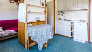 A compact room with a bed, a small table, a kitchenette, and a wooden shelf unit. - Cozy Studio for 2 with Terrace, Ski-in/Ski-out, Close to Shops - Montchavin La Plagne (La Plagne Montchavin Les Coches)