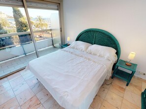 A bedroom with a bed, two bedside tables, a window with a view, and a balcony.