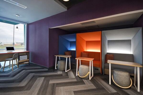 A modern office space with a desk, two tables, and a couch.