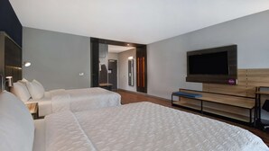 Una habitación de hotel con dos camas, televisión, escritorio y espejo.
