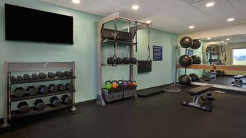 Un gimnasio con racks para pesas, kettelbells y equipo de ejercicio.