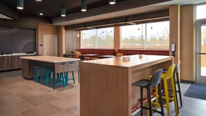 Un área de cocina moderna con una isla central, taburetes de bar y una zona de estar con bancos rojos.