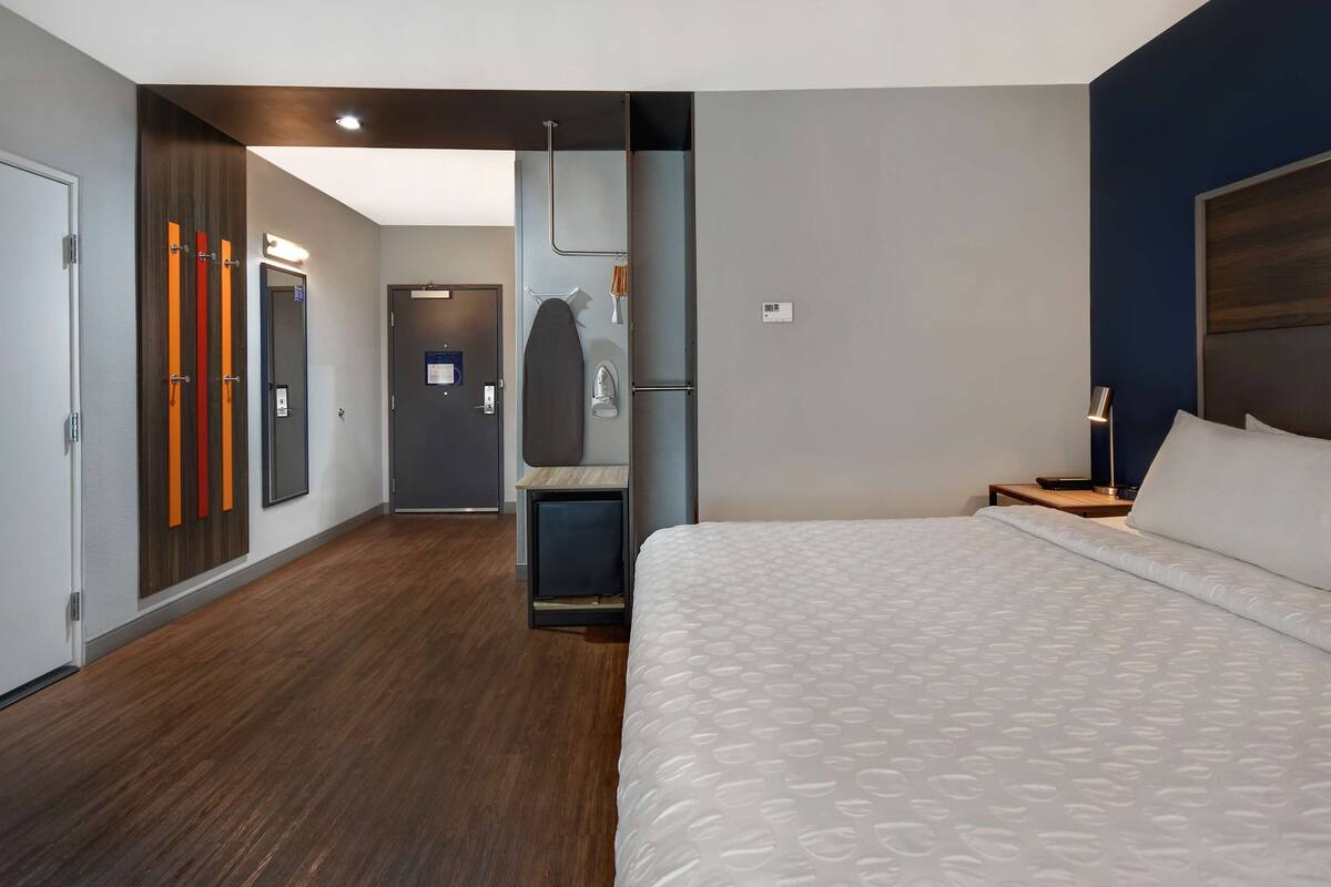 Une chambre d’hôtel avec un grand lit, un bureau et une armoire.