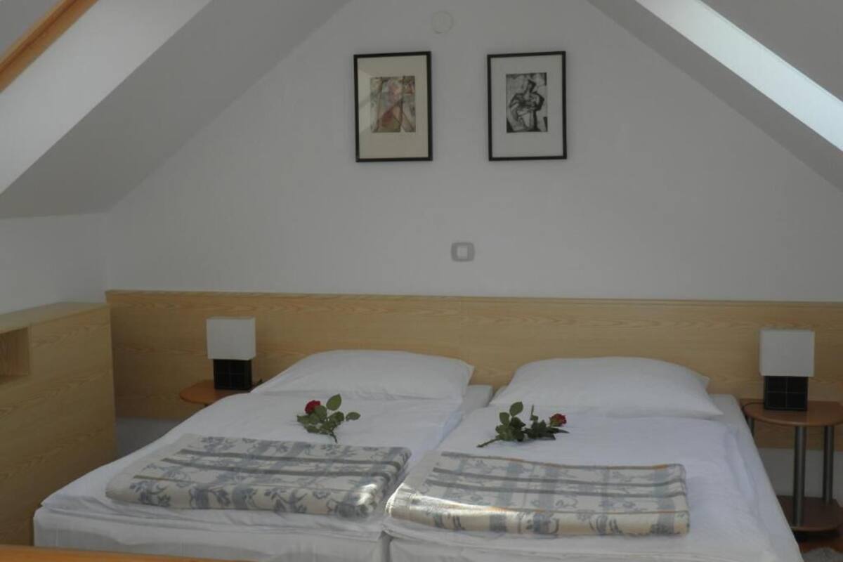 A bedroom with two beds, each with a pillow and a small table beside it.