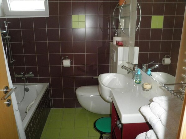 A bathroom with a bathtub, toilet, sink, and a mirror.