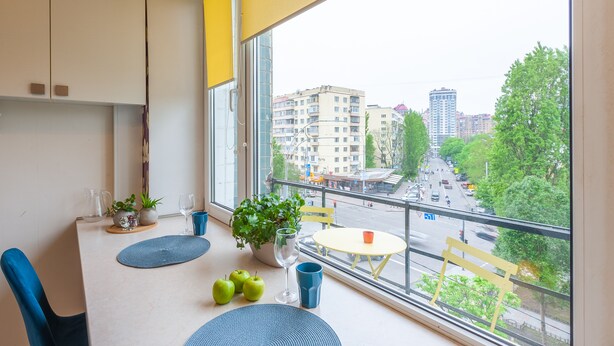 A balcony with a table, chairs, potted plants, and a view of the cityscape. - MalinaApt Botanical apartment (Kyiv)