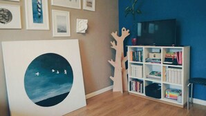 A room with a bookshelf, a painting, and a television. - MalinaApt Sea Place (Kyiv)