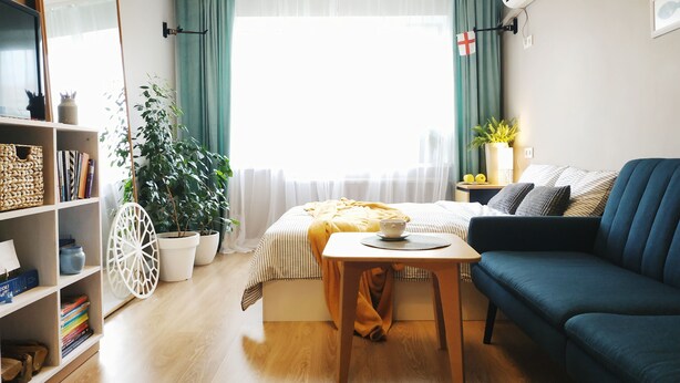 A well-lit room with a bed, a blue sofa, a wooden table, and a bookshelf. - MalinaApt Sea Place (Kyiv)