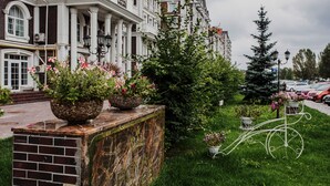 Een gebouw met klassieke architectuur, een bakstenen fundering en een balkon met potplanten.