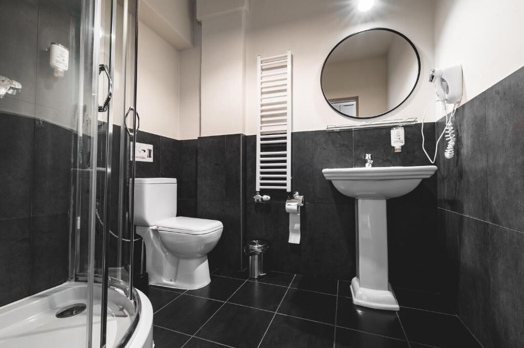 A modern bathroom with a glass shower enclosure, a toilet, a sink, and a towel rack.