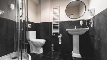 A modern bathroom with a glass shower enclosure, a toilet, a sink, and a towel rack.