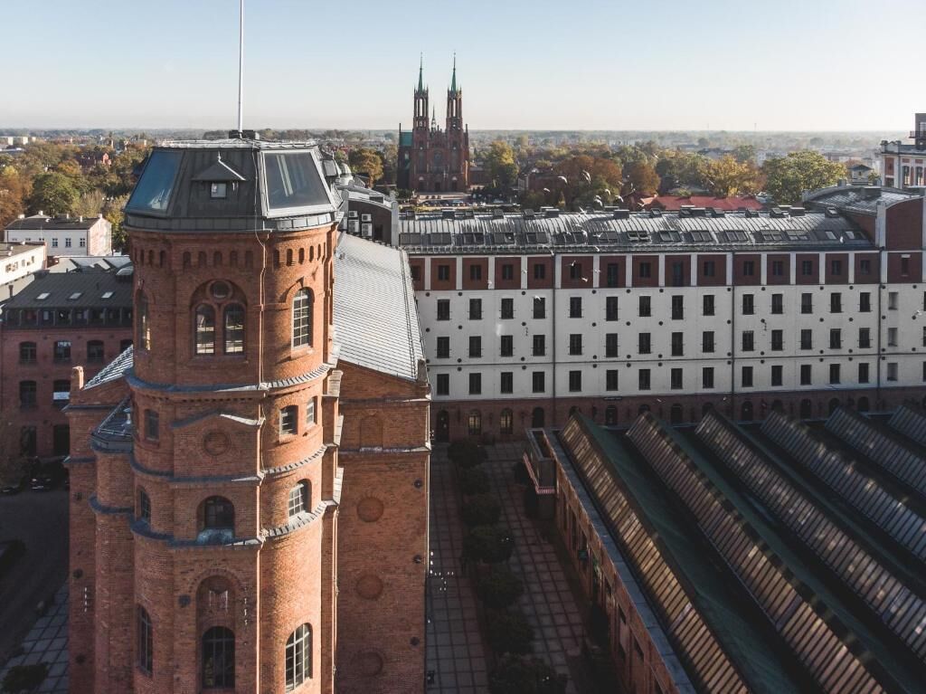 En historisk byggnad med ett markant torn och en stor, modern tillbyggnad med ett rutmönster av fönster.