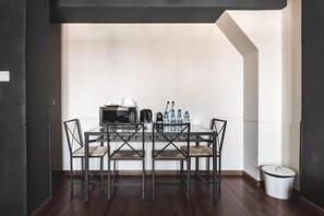 A dining area with a glass table, four chairs, a microwave, a kettle, and a water dispenser. - Aparthotel Stara Przędzalnia (Żyrardów)