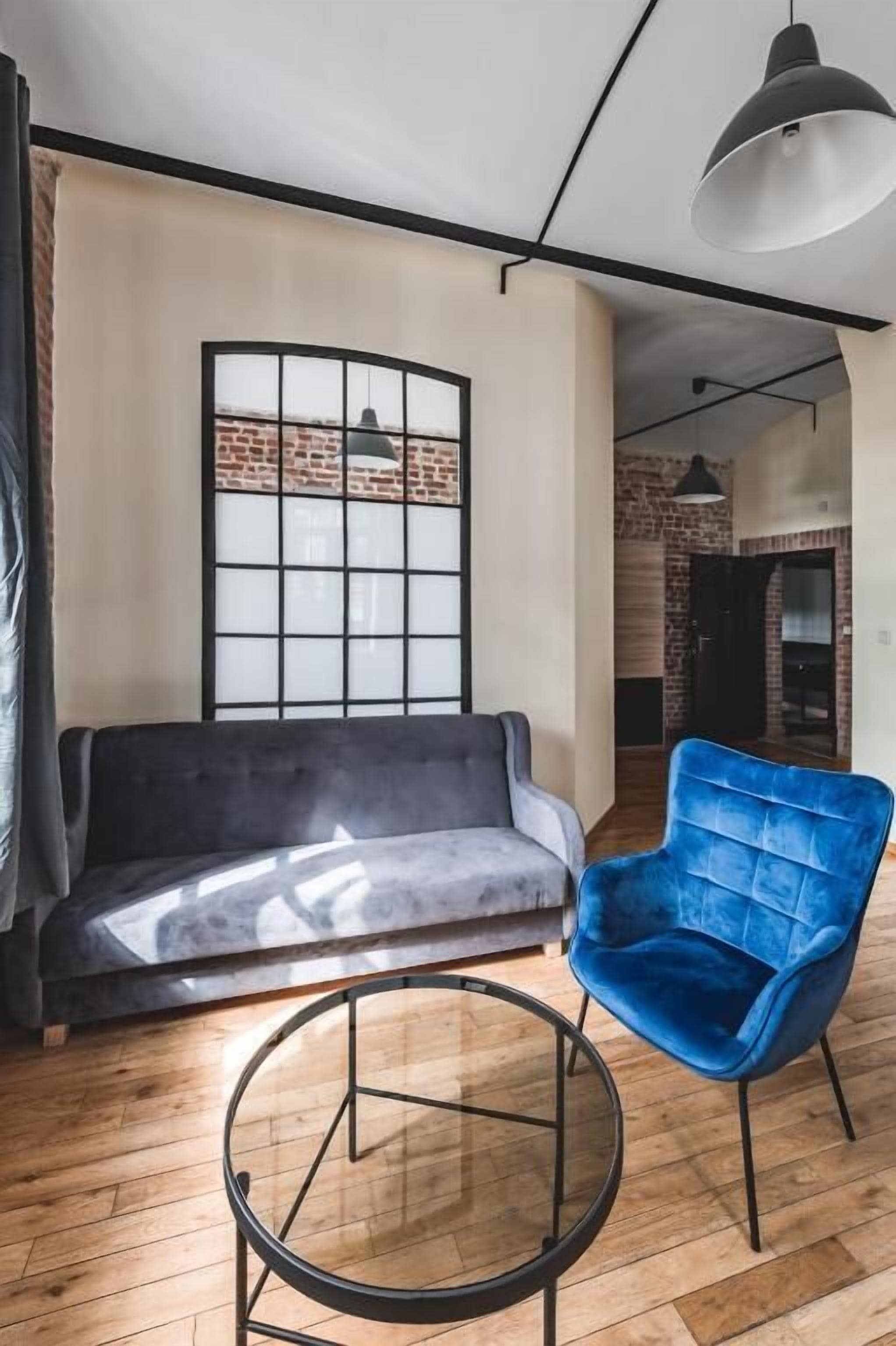A modern living room with a dark sofa, a blue armchair, and a round coffee table.