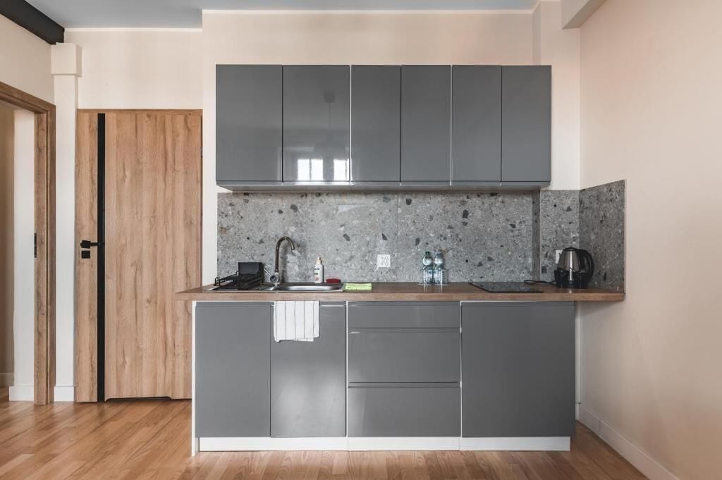 Una cocina moderna con gabinetes grises, una encimera de granito y un horno empotrado.