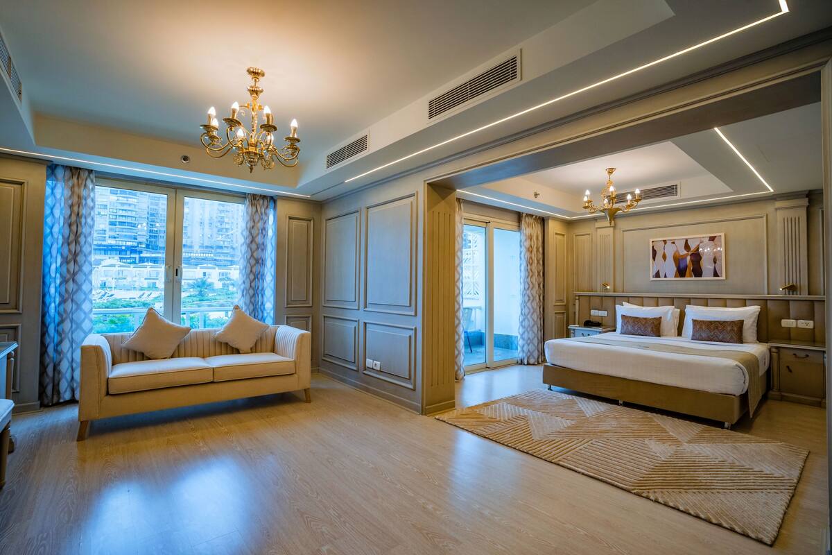 Une chambre spacieuse avec un grand lit, un canapé et une vue sur la ville.
