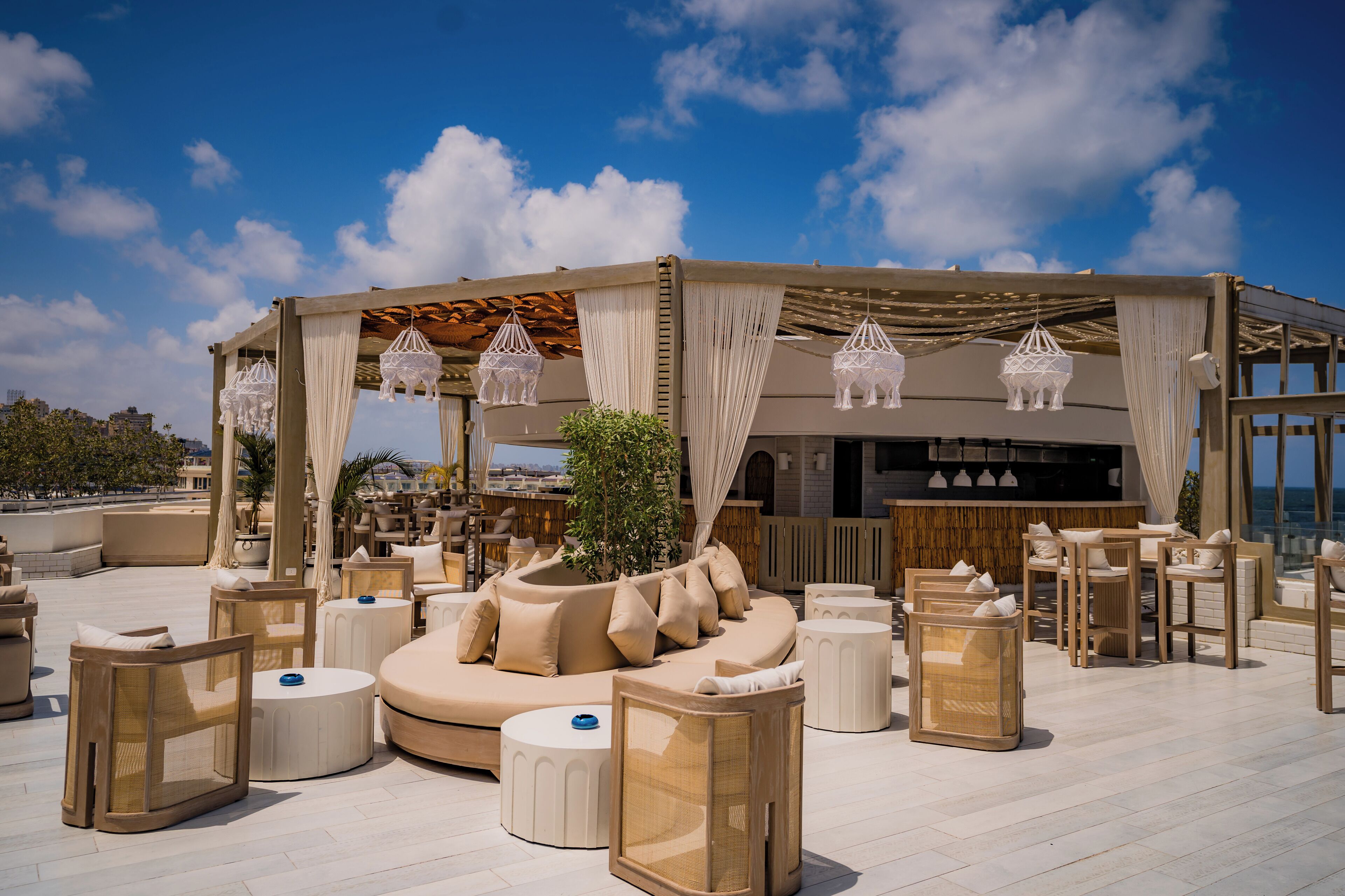 An outdoor lounge area with a variety of seating options, including sofas and chairs, under a covered pergola.